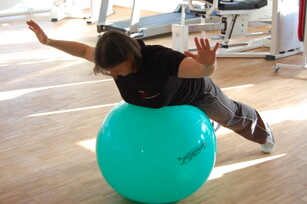 Bild zeigt eine Frau die mit einem Gymnastikball trainiert.