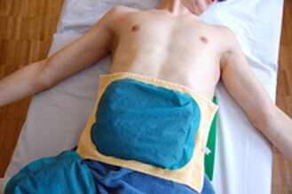 Bild zeigt eine Warmpackung auf dem Bauch des Patienten.